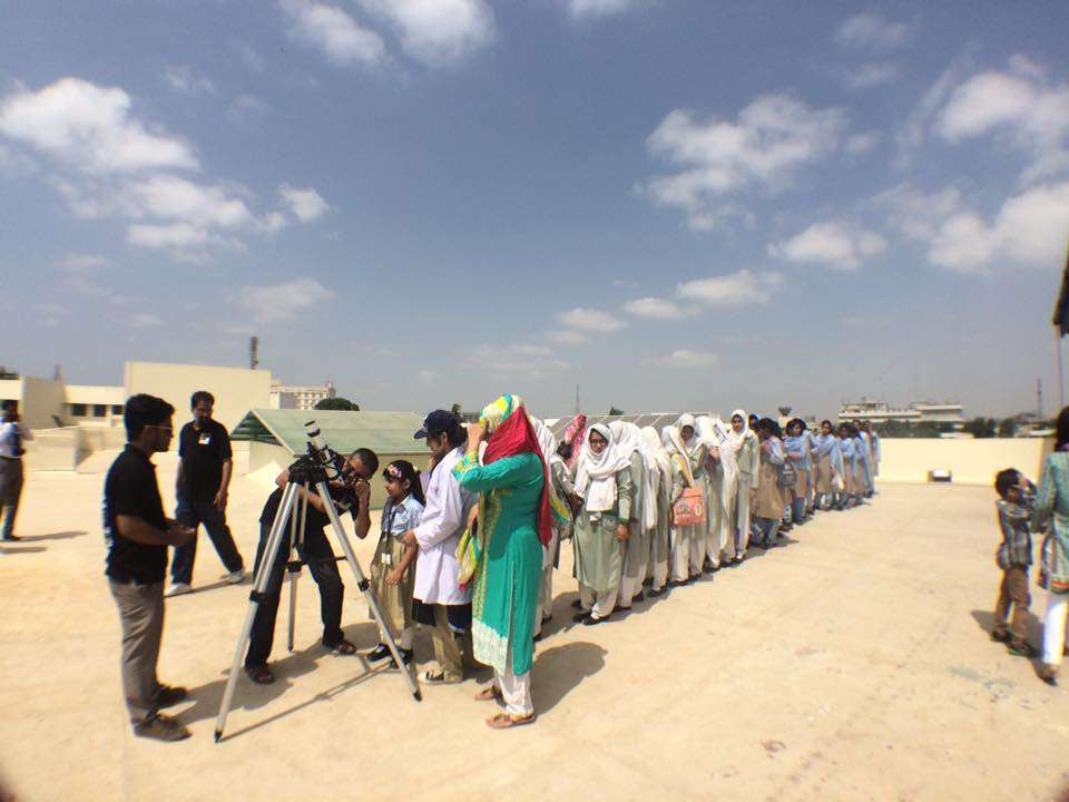 Students taking turns observing through a telescope during an astronomy education session